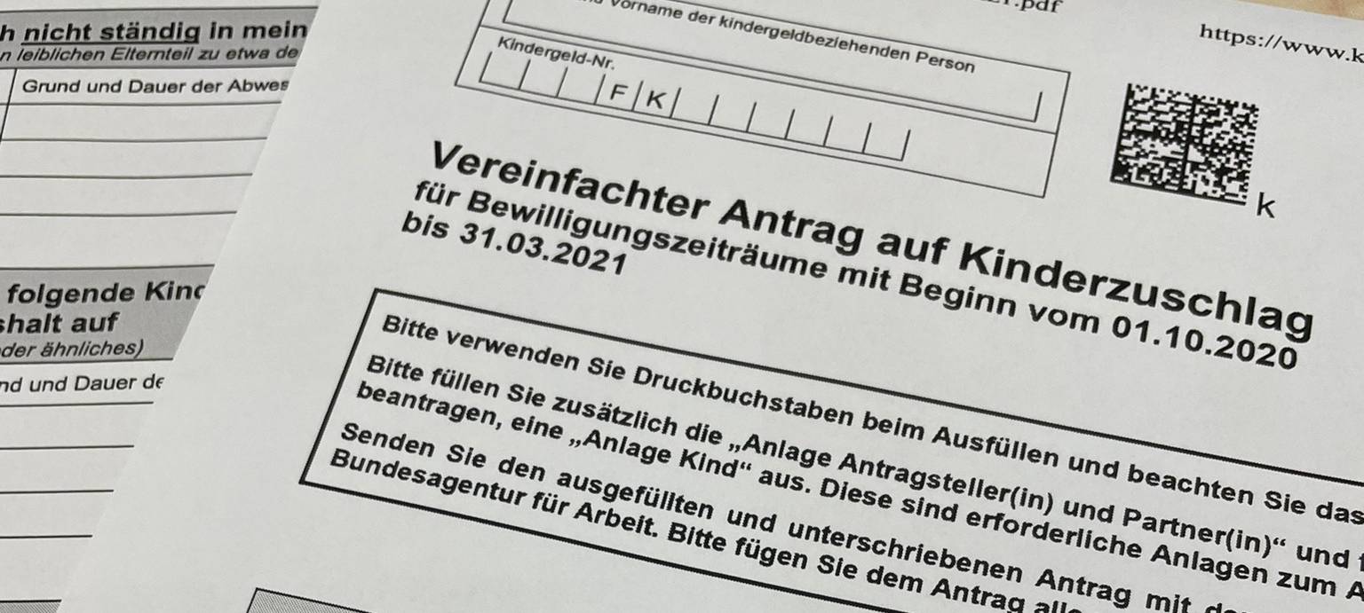 Formular für die Beantragung des Kinderzuschusses liegt ausgedruckt auf einem Tisch, ein pinker Kuli mit Radio MK Logo liegt darauf